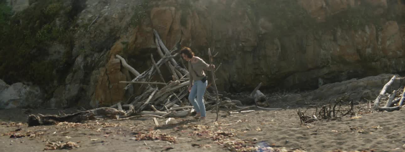 A woman picks up driftwood