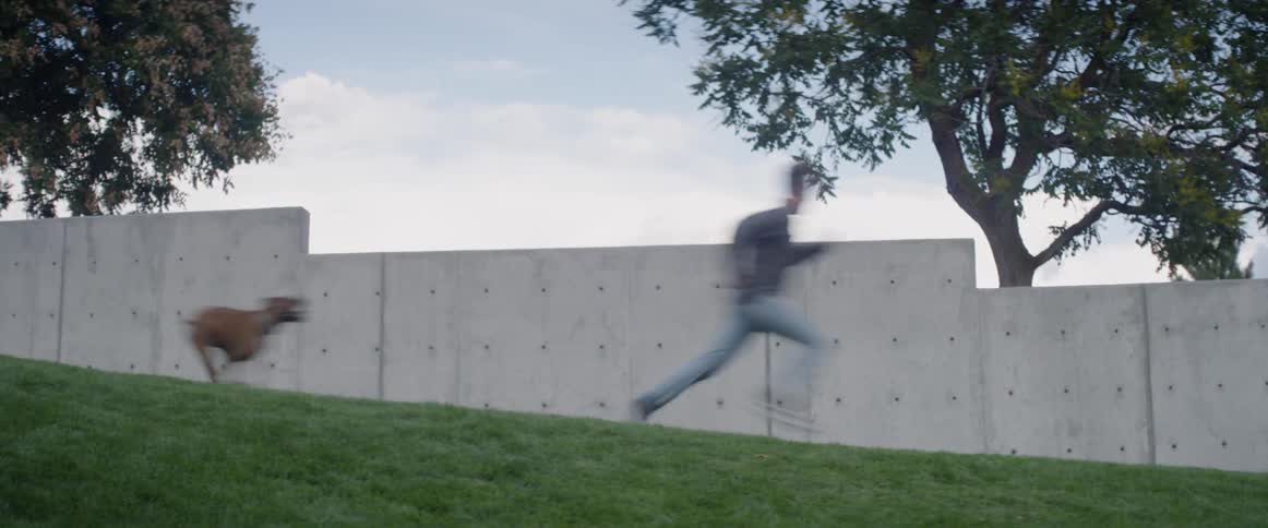 Man runs from dog past concrete wall