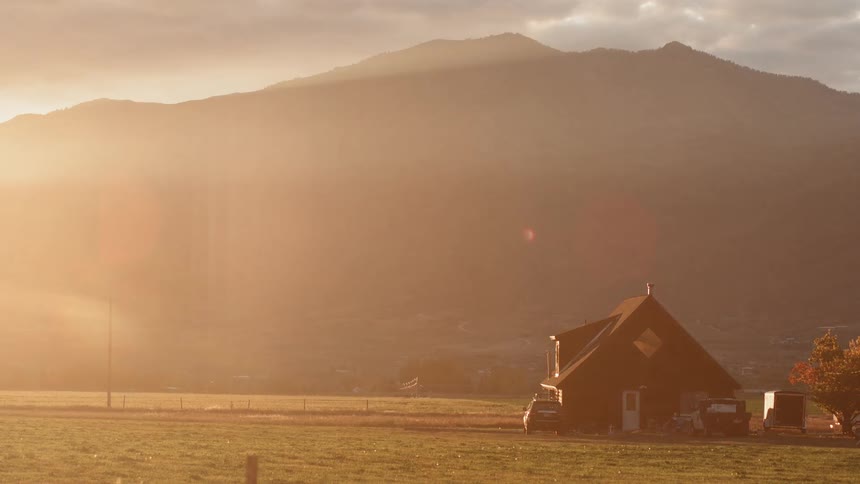 The sun sets over a rural house