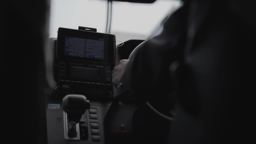A navigation system is operating as a man is driving a vehicle in a city in daylight
