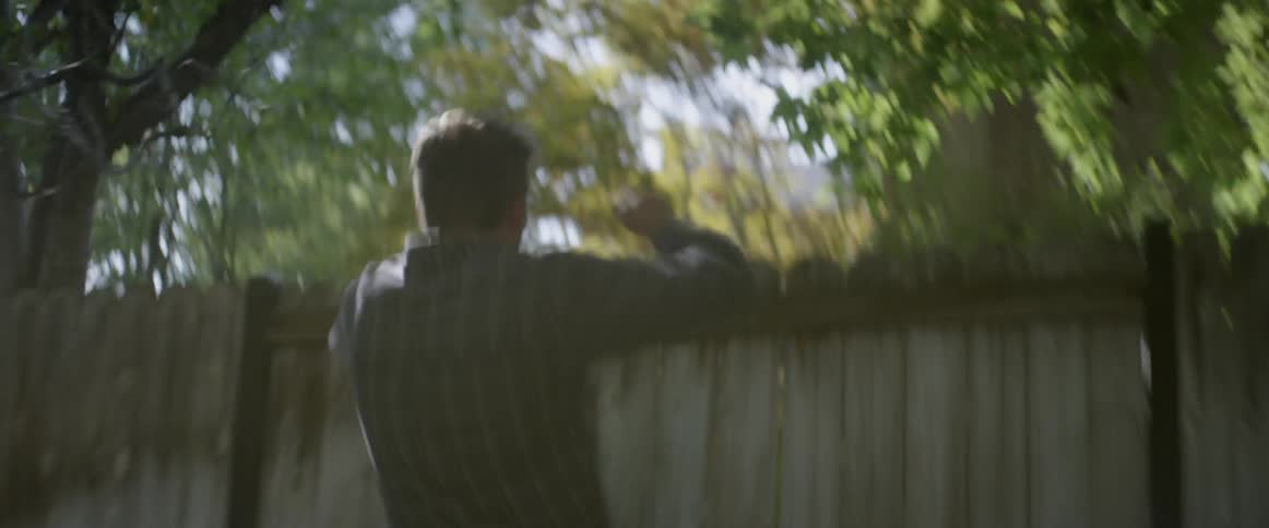 Man sprints across a yard and jumps over a fence