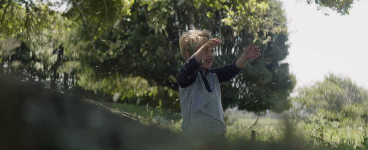 A young boy plays as debris is blown at him outside