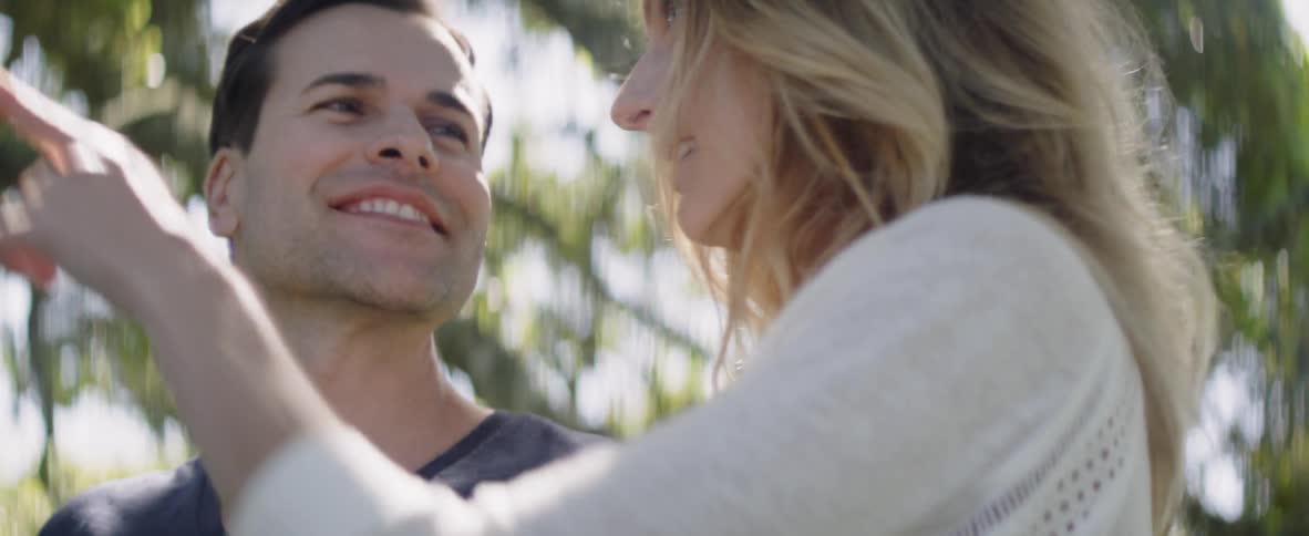 Man and woman smile and stand in the woods
