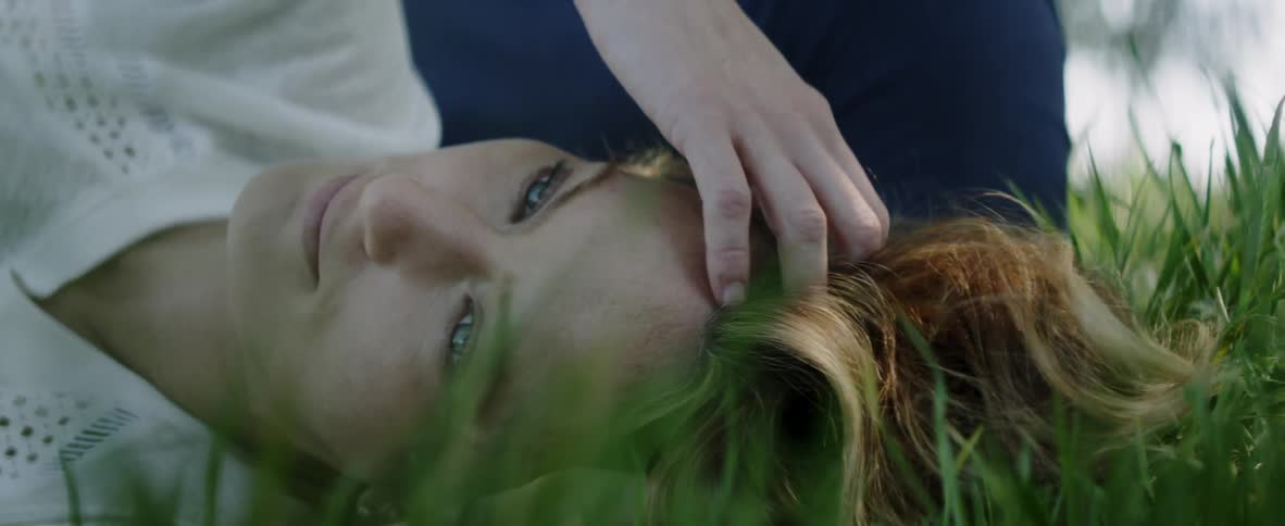 Woman laying in the grass is running her fingers through her hair