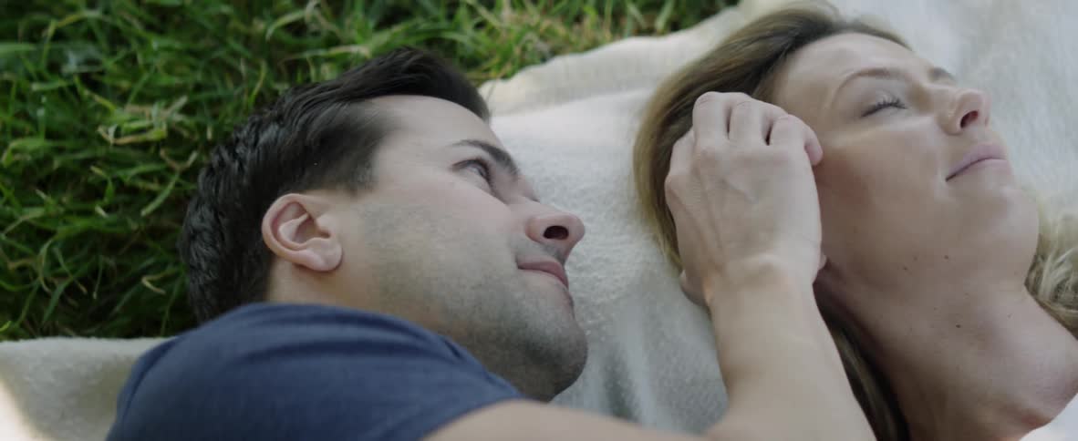 A man and woman lay together in the grass