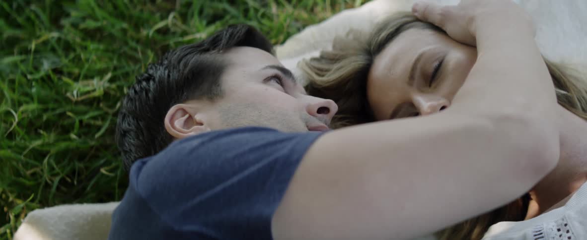A man and woman lay on the grass together