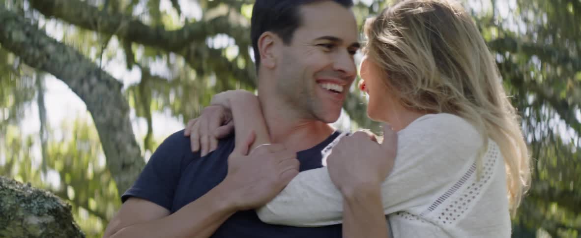 Woman sneaks up behind man and embraces him outside