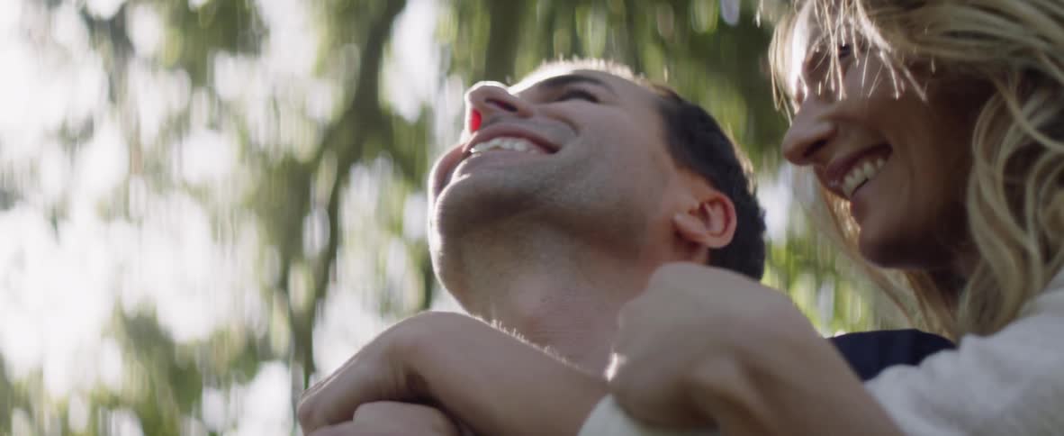 A man and woman hug under the trees