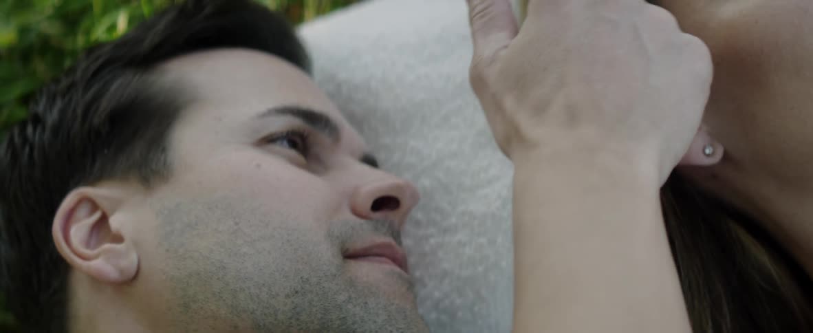A man and woman cuddle on a lawn