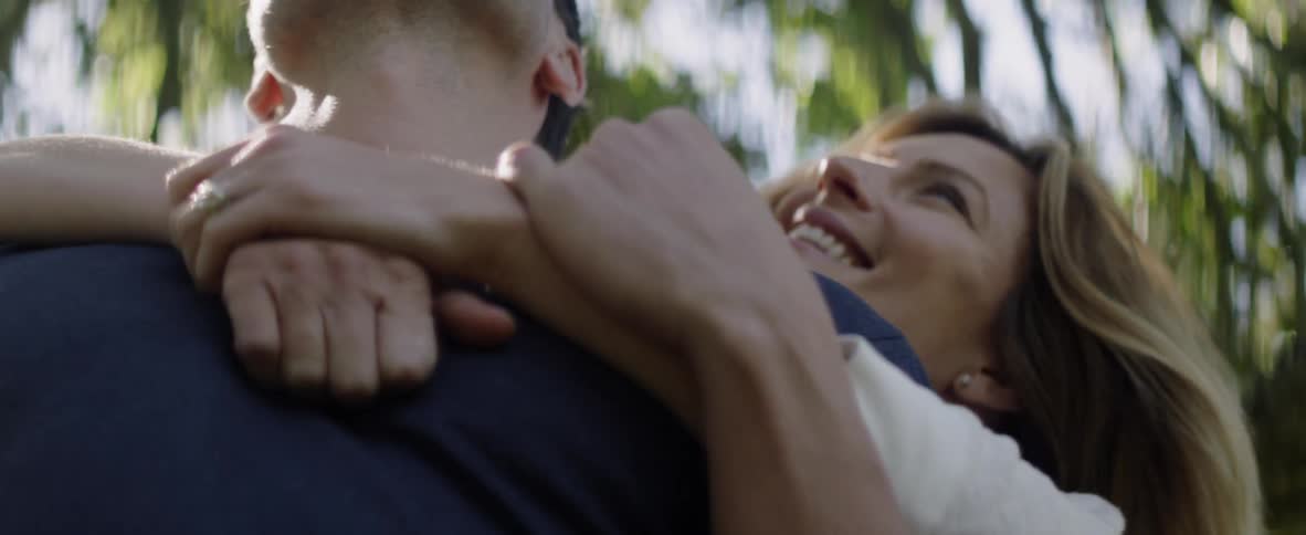 Man and woman are smiling and embracing outside on sunny day