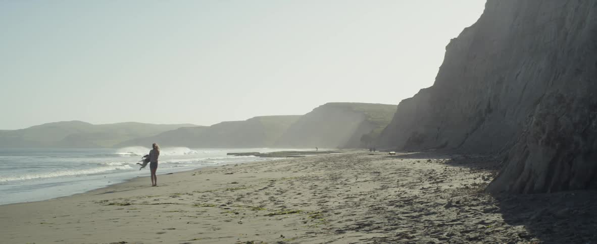 A mother is swinging her child in circles on a beach in daylight