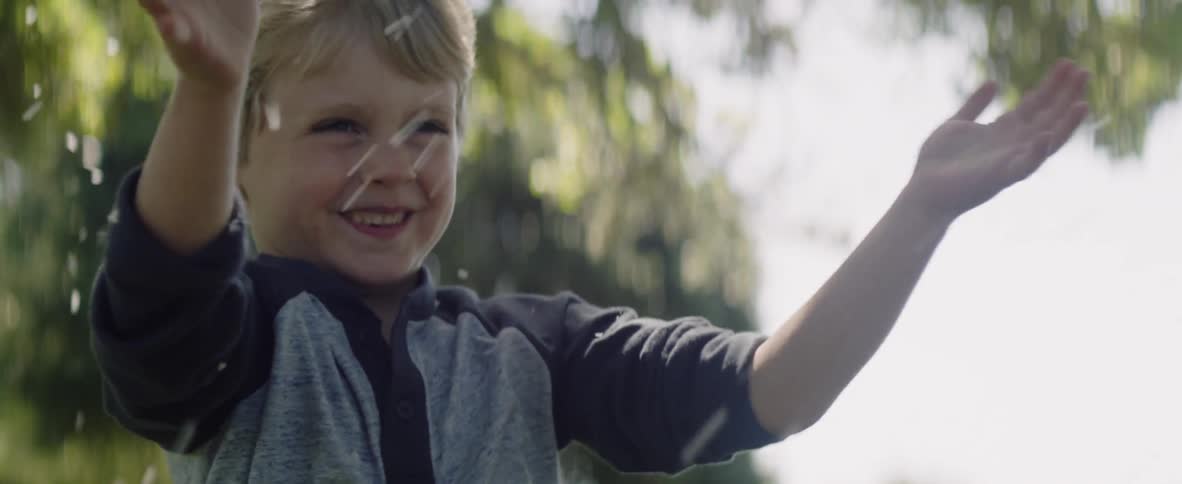 Child smiles and waves his arms shavings swirl around him