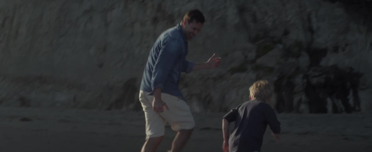 Father and son running and playing on ocean beach