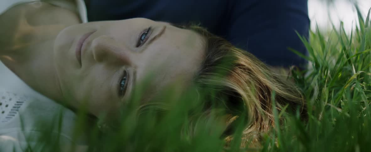 Woman laying down in the grass opens her eyes