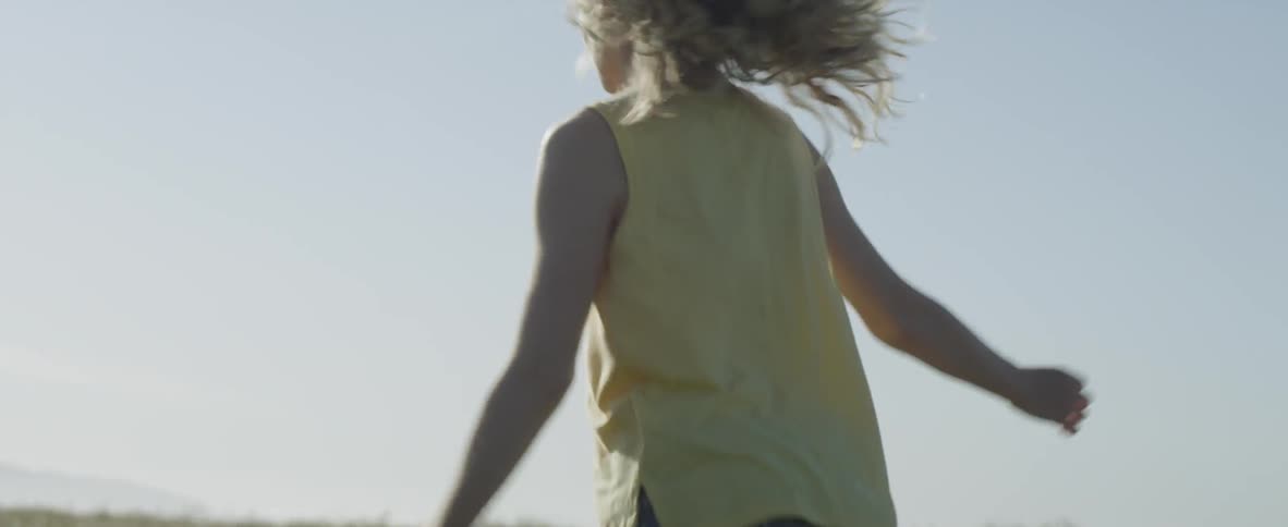 Little girl running through grassy pasture on sunny day