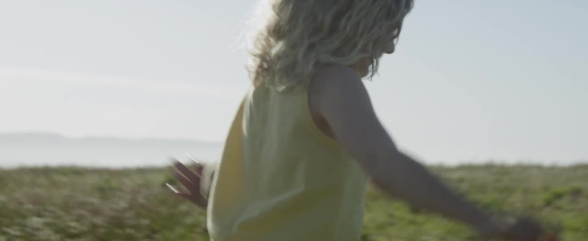 A girl runs in a field with her arms outstretched