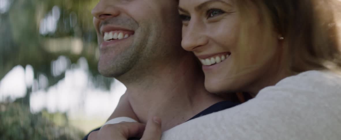 A couple are hugging and laughing outside in daylight