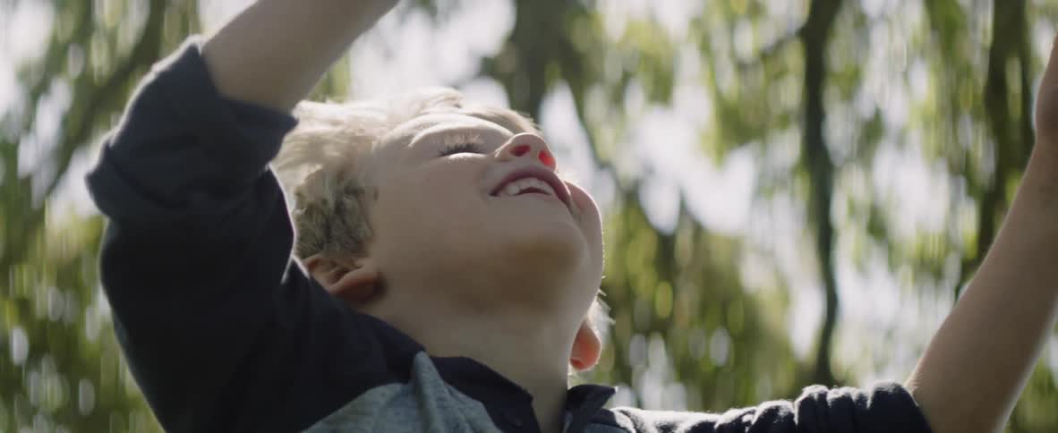 Child smiles and waves his arms shavings swirl around him