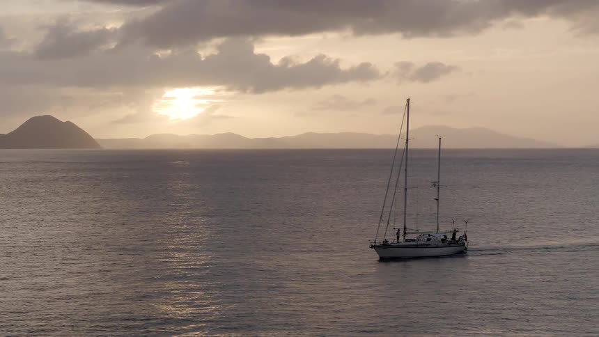 Boat sailing on open ocean waters at sunset on cloudy evening