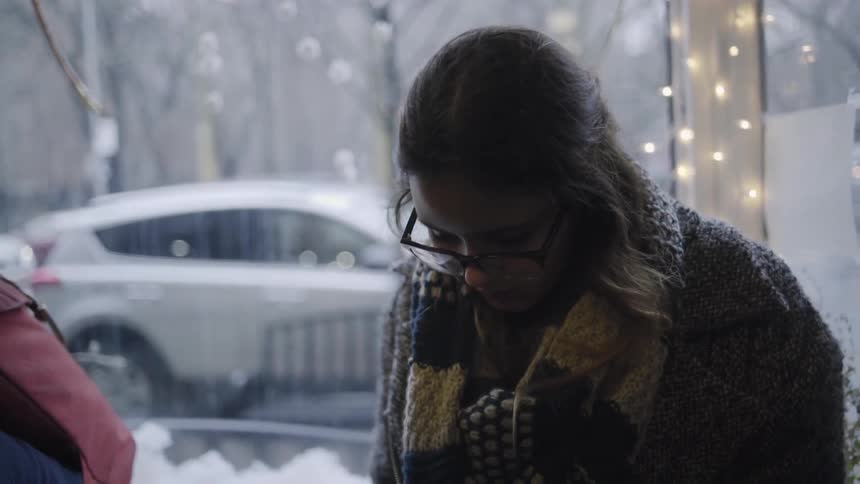 A woman sits with her down in a business as vehicles pass by