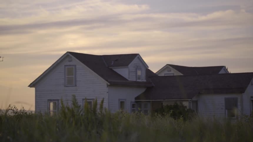 View of an old, white farmhouse under a cloudy sky at dusk