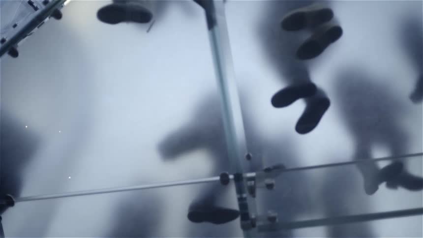 People walking across a piece of glass