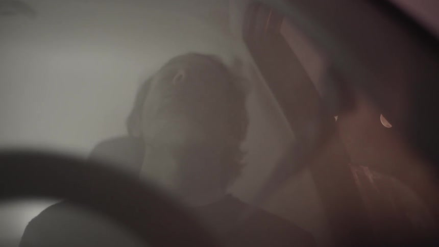 A man sits in a car that is filled with smoke