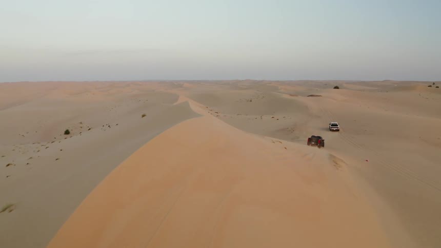Trucks travel over sand dunes in the desert
