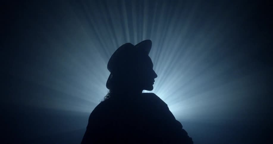 Flashing lights silhouette a person in a dark room