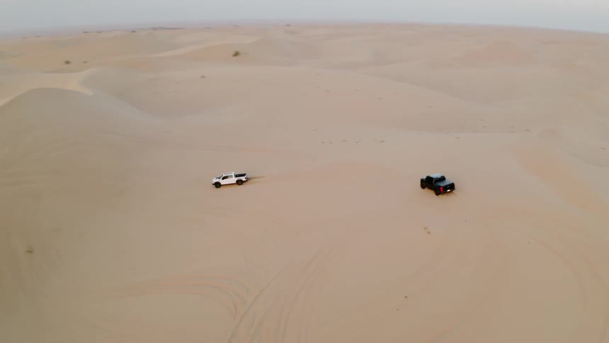 The cars spin around driving up dunes in the desert