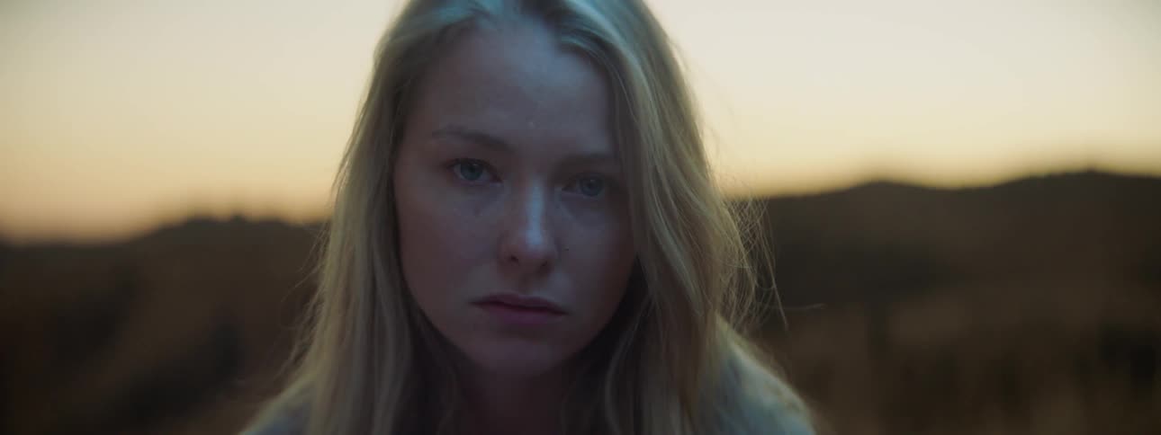 Woman looks sad while standing outside at sunset