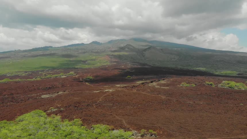 Hilly dirt and grass covered land with clouds overhead