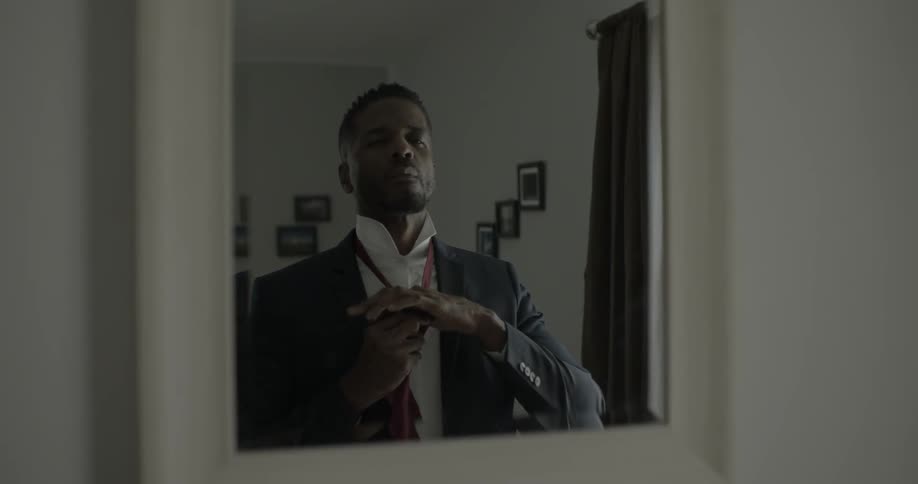 A man looks in a mirror as he ties his necktie