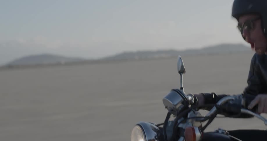 A man rides a motorcycle across a desert