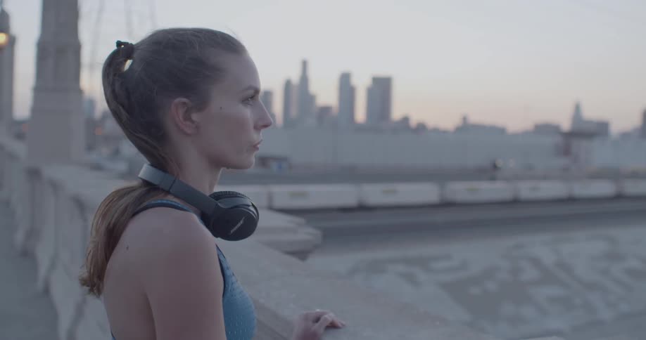 Woman wearing headphones looks out at the city