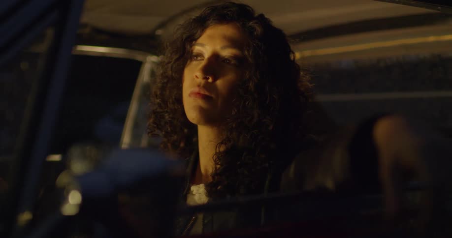 A woman sits in a car at night