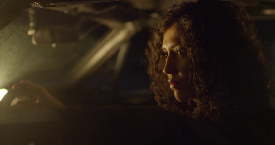 Woman stands next to a vehicle at night