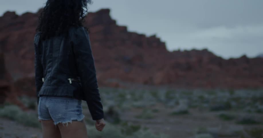 A woman is standing in the desert on a cloudy day