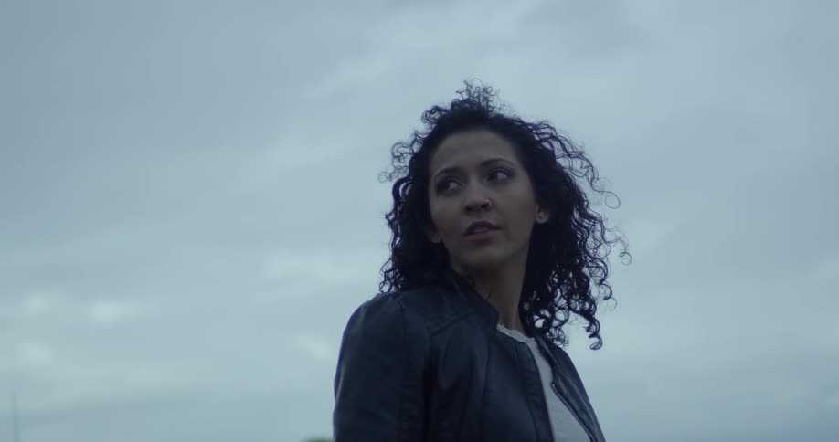 A woman standing outside on a cloudy day is looking at her surroundings