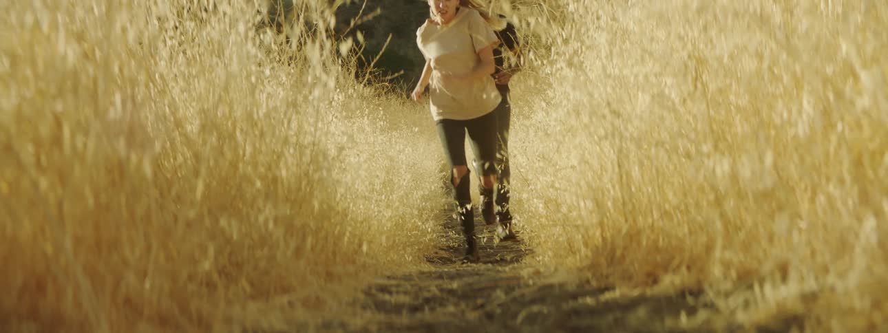 A man and woman run through a rural field