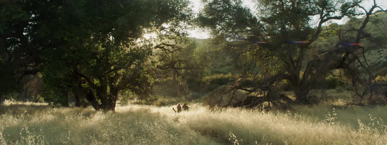 Two people sit in a rural field at sunset