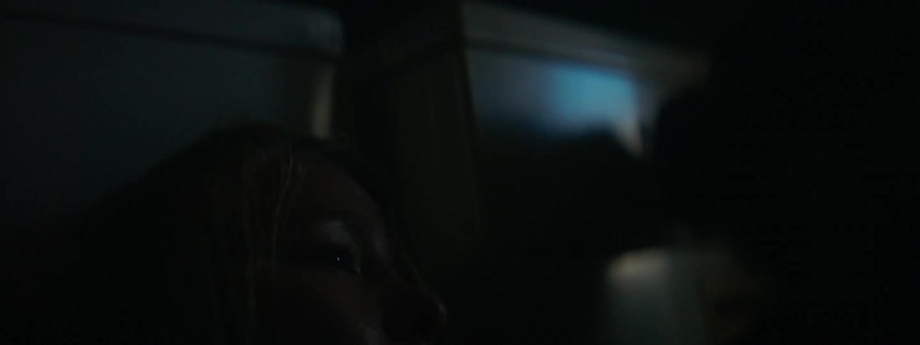 Light shines through a window onto a woman's face at night