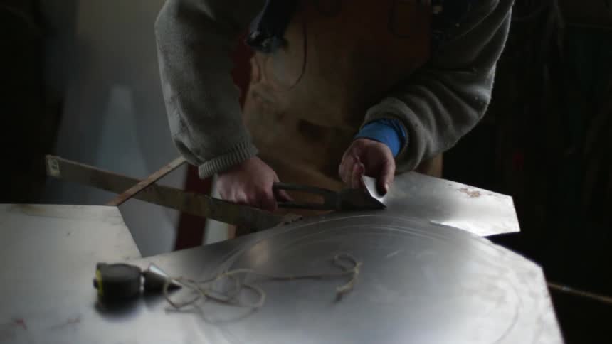 A blacksmith cuts a sheet of metal