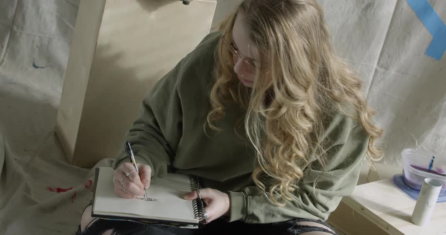 Artist Student writing in a notebook in her bedroom