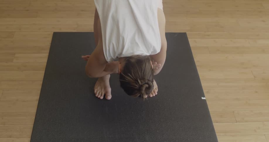 Woman is stretching forward on yoga mat in gym exercise room
