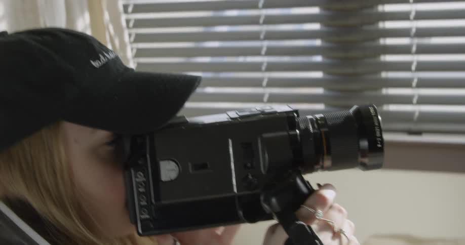 A woman with a video camera films inside a room