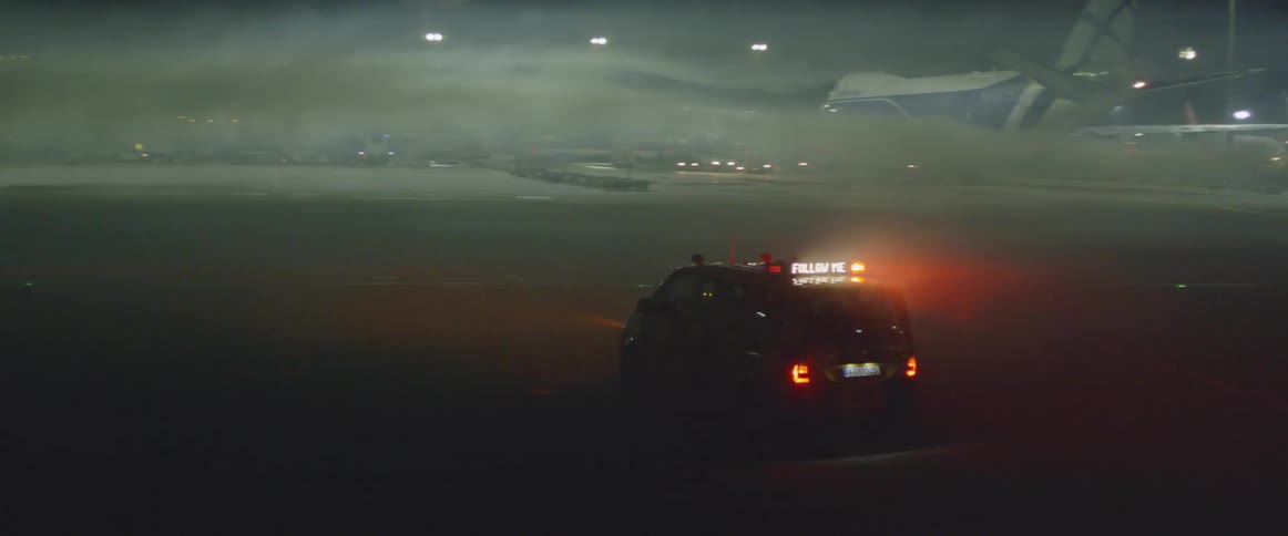 A van with flashing lights is driving at an airport at night