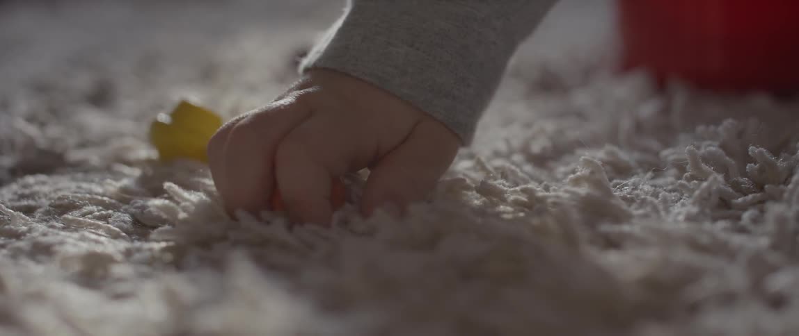 A toddler picks up a toy from the floor
