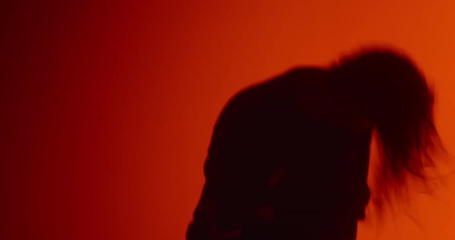 A man head bangs in a dark room