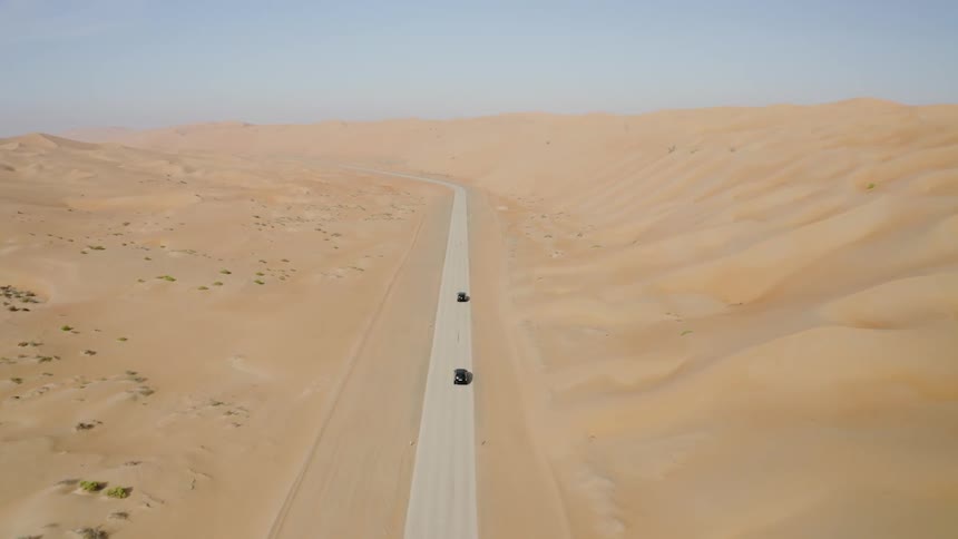 Two cars drive on a desert road